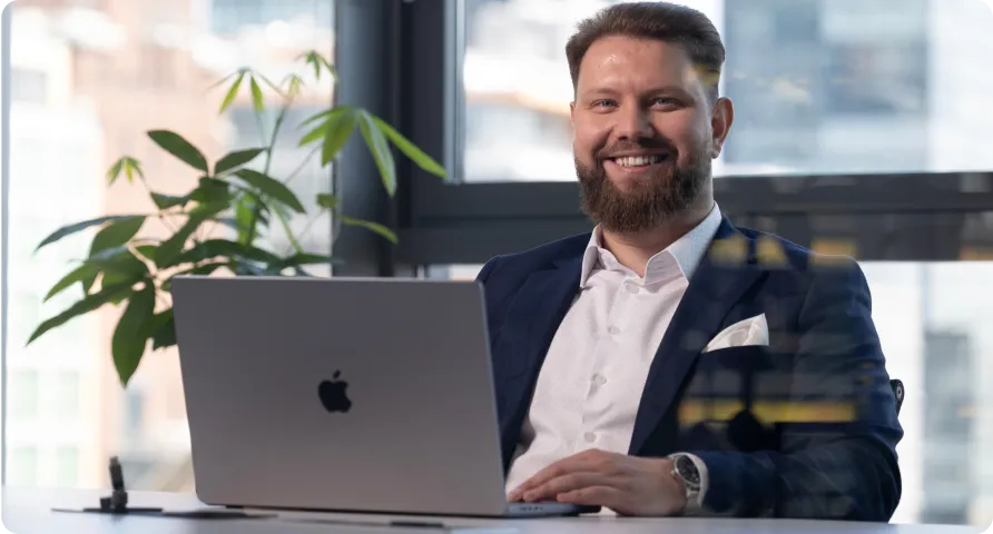 A businessman sitting behind a laptop and smiling